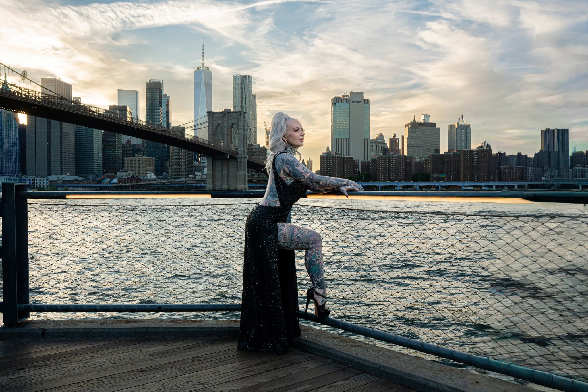 Portrait in a black gown beside the waterfront with the Brooklyn Bridge and skyline at sunset