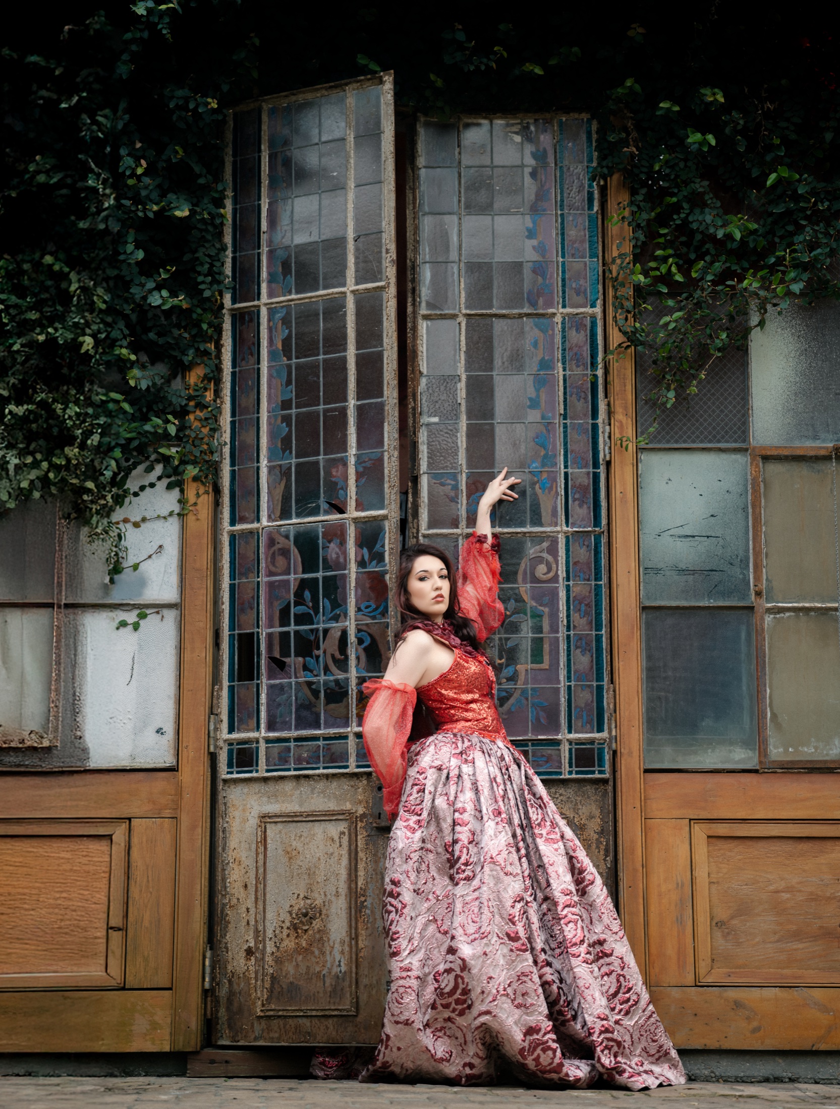 Creative portrait in a red and pink gown against antique windows